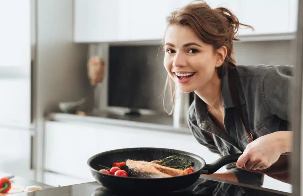 About Me 2 Clara Dellucci cooking low-carb salmon and vegetables in a modern kitchen